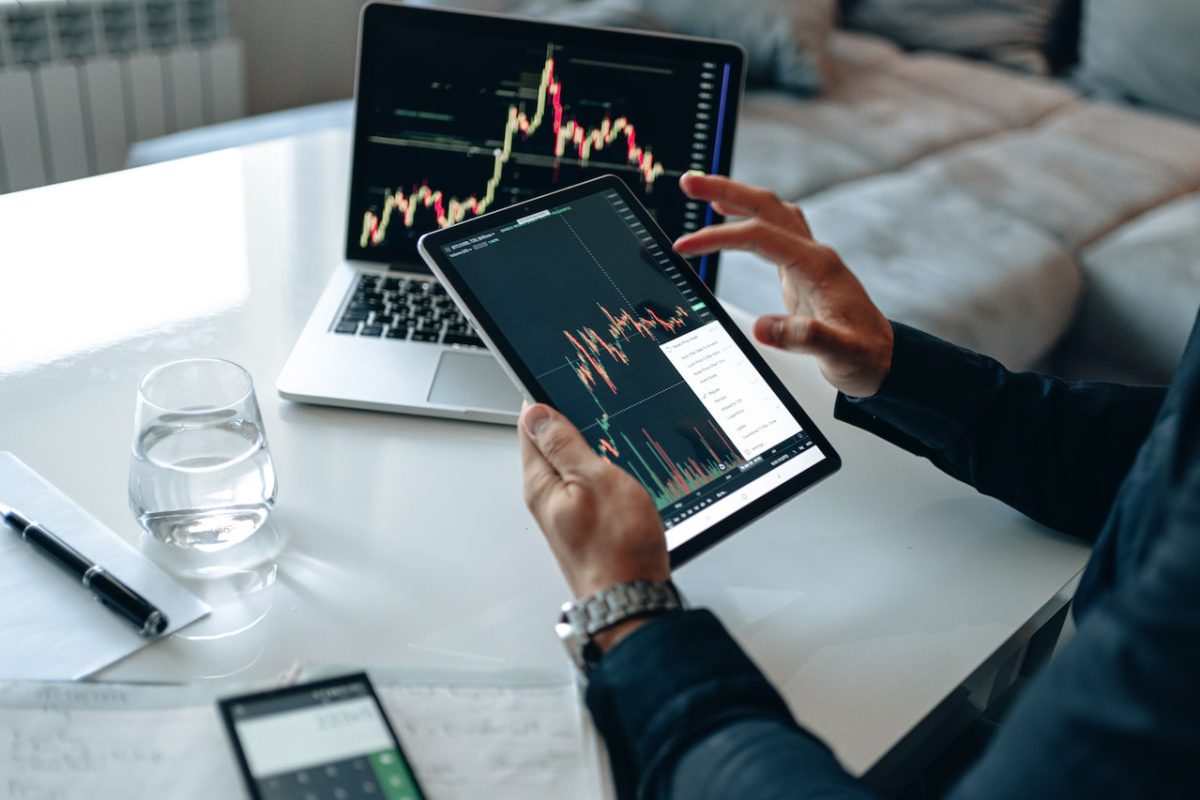 Photo by George Morina: https://www.pexels.com/photo/a-person-in-blue-long-sleeves-holding-a-tablet-with-cryptocurrency-graph-neat-laptop-on-the-table-4960464/